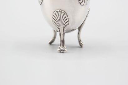 Coquetier tripode en argent à décor de coquilles....