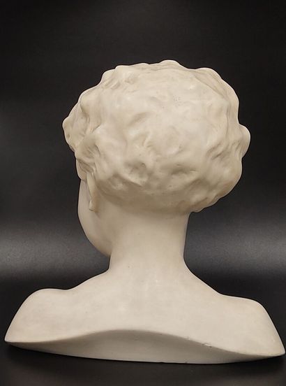 A wax bust of a laughing child on a wooden...