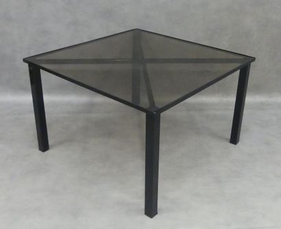 A wrought-iron coffee table with smoked glass...