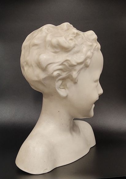 A wax bust of a laughing child on a wooden...