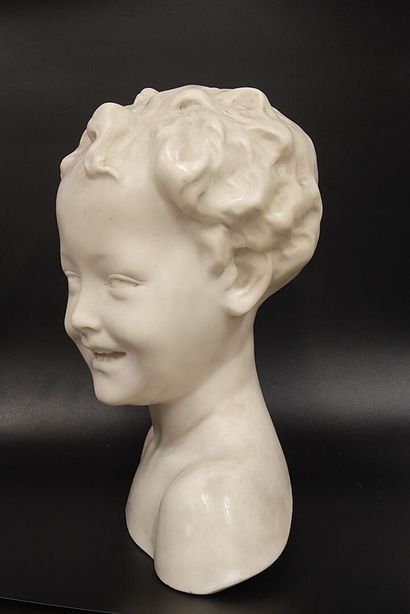 A wax bust of a laughing child on a wooden...