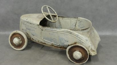 A white-painted sheet metal pedal car 
Oxidation...