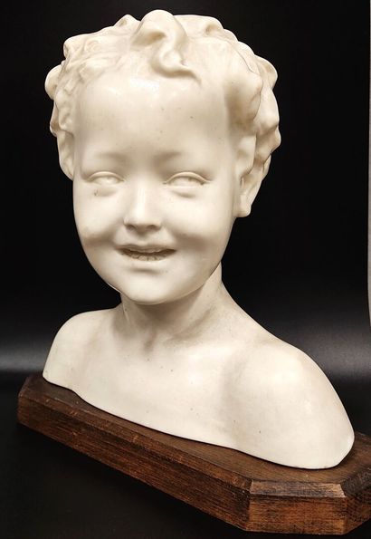 A wax bust of a laughing child on a wooden...
