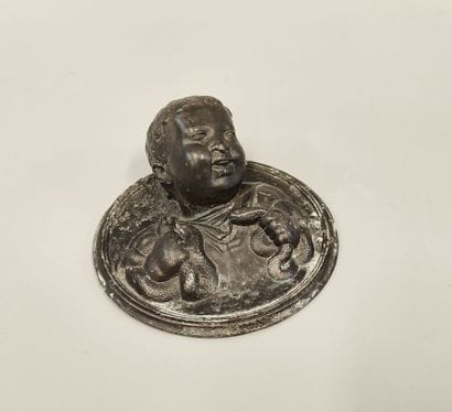 Patinated metal medallion in the round featuring...
