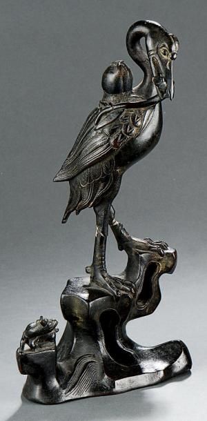 Grue en bronze, dressée sur un rocher, tenant...
