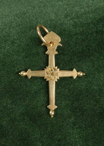 A flat 750 gold cross featuring a flower...