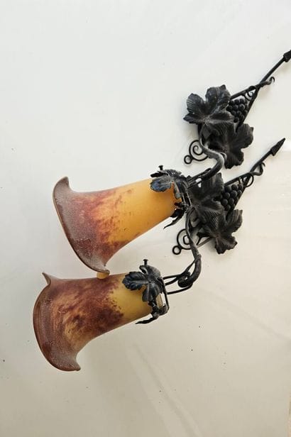 Two blackened metal wall sconces holding...