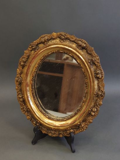 SMALL oval mirror in carved and gilded wood...