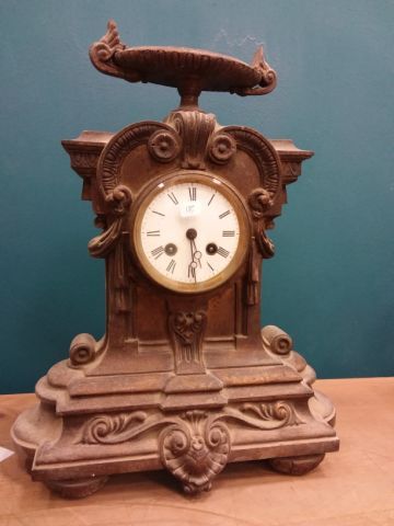 PENDULE en fonte de fer surmonté d'un pot...