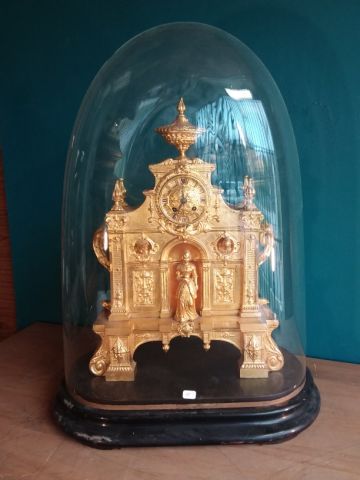 PENDULE en métal doré sous globe à décor...