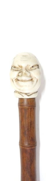 Wooden cane (bamboo?), the pommel in carved...