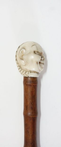 Wooden cane (bamboo?), the pommel in carved...