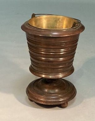 Molded mahogany bucket resting on a pedestal...