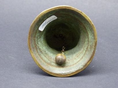 Cloche en bronze patiné à fretel anthropomorphe,...
