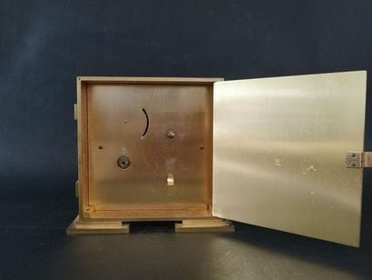 Horloge carré en métal doré. Numérotée sous...