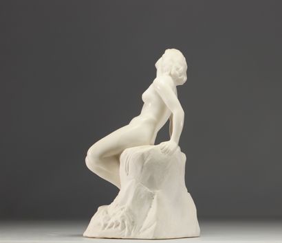 Jeune femme nue assise sur un rocher se lovant...