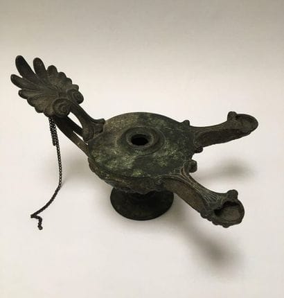 Bronze oil lamp with a green patina having...