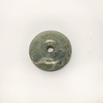 Nebulous green translucent chalcedony disc.

Undetermined...