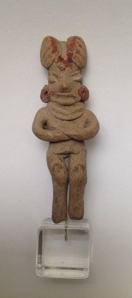 Female figurine standing with crossed arms...