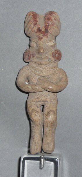 Female figurine standing with crossed arms...