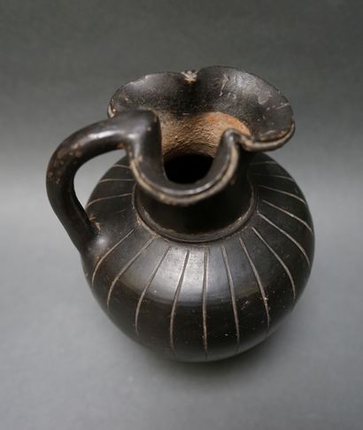A black ceramic oenochoe with a trefoil spout...