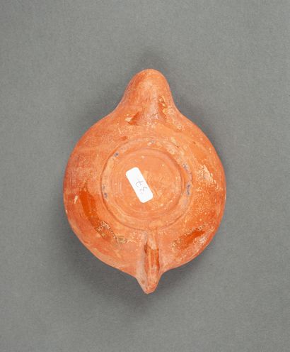 A red terracotta oil lamp with a round spout...