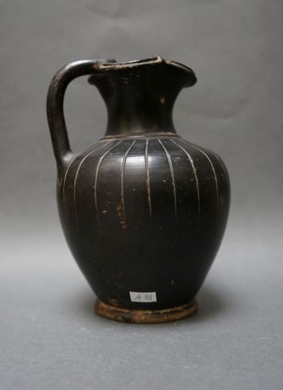 A black ceramic oenochoe with a trefoil spout...