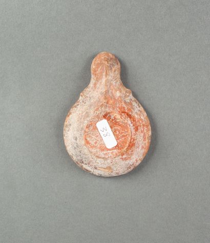A red terracotta oil lamp with a scrolled...