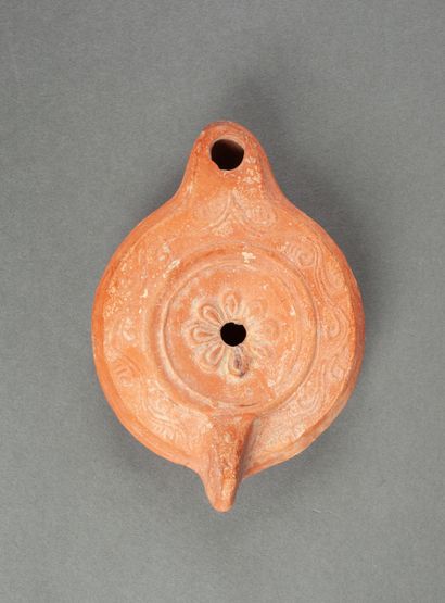 A red terracotta oil lamp with a round spout...