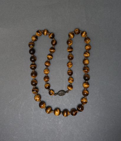 Long necklace made of round pearls in tiger's...