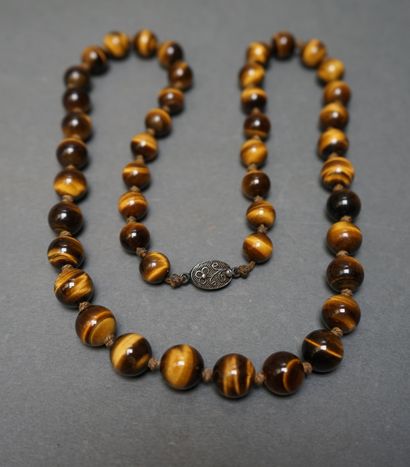 Long necklace made of round pearls in tiger's...