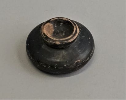 Black glazed terracotta bowl on pedestal.

Gnatia,...