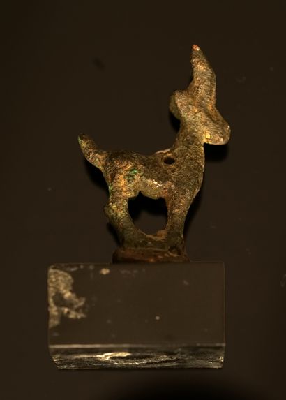 Amulette en bronze patiné présentant un cervidé....