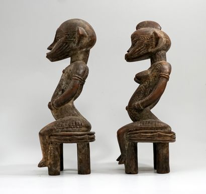 Couple représenté assis sur des tabourets...