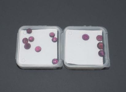 Set of 2 boxes of round-cut, flat-table rhodolite...