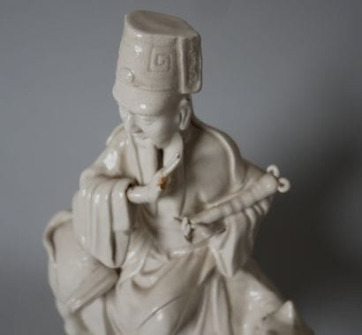 White porcelain statuette of an old man sitting...