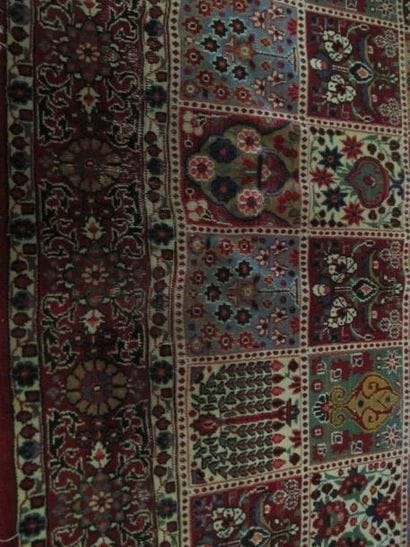 Grand tapis à fond rouge à décor d'un damier...