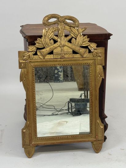 Miroir en bois doré à décor d'attributs de...