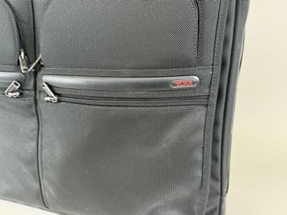 TUMI.
Valise roulante en toile noire.
48...