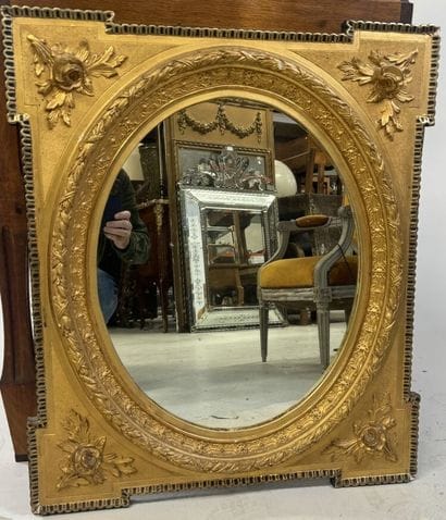 Wood and gilded stucco mirror with oval view,...