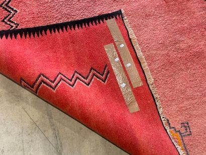 Grand tapis sur fond orangé à décor de motifs...