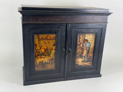 Small cabinet in blackened wood opening with...