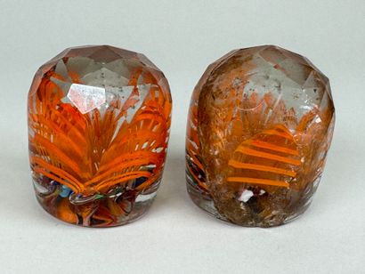 Two faceted and colored glass paperweight...