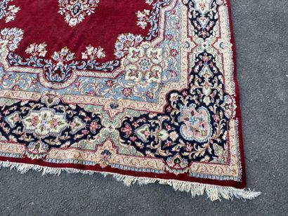 A large hand-knotted wool rug featuring a...
