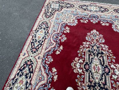 A large hand-knotted wool rug featuring a...