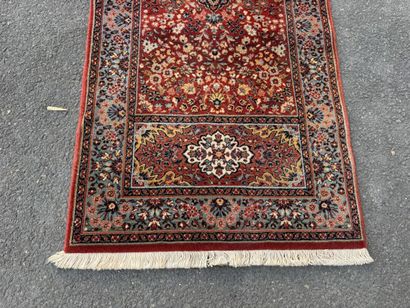 Machine-woven rug with a red background featuring...