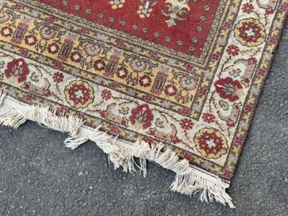 Hand-knotted wool rug featuring a red background...