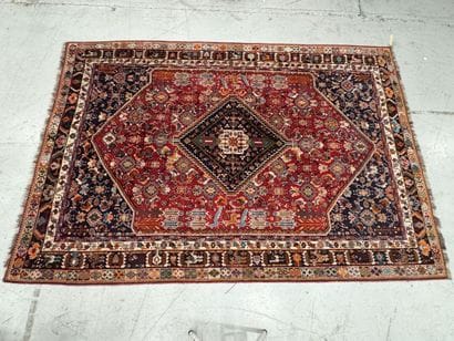 A large hand-knotted wool rug featuring stylized...