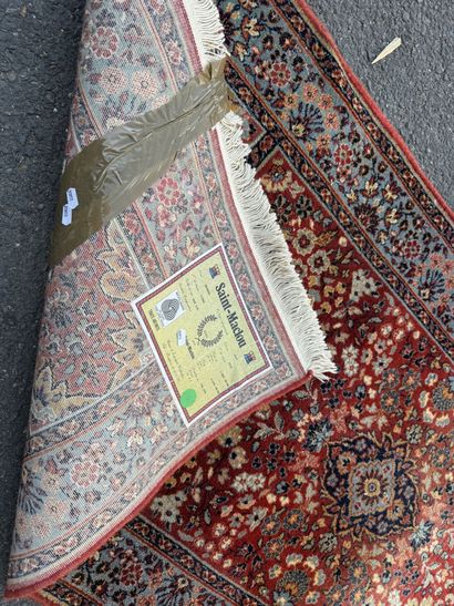 Machine-woven rug with a red background featuring...