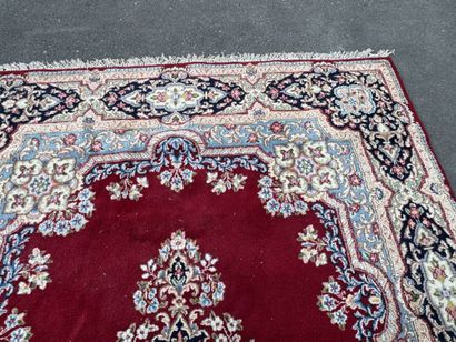 A large hand-knotted wool rug featuring a...
